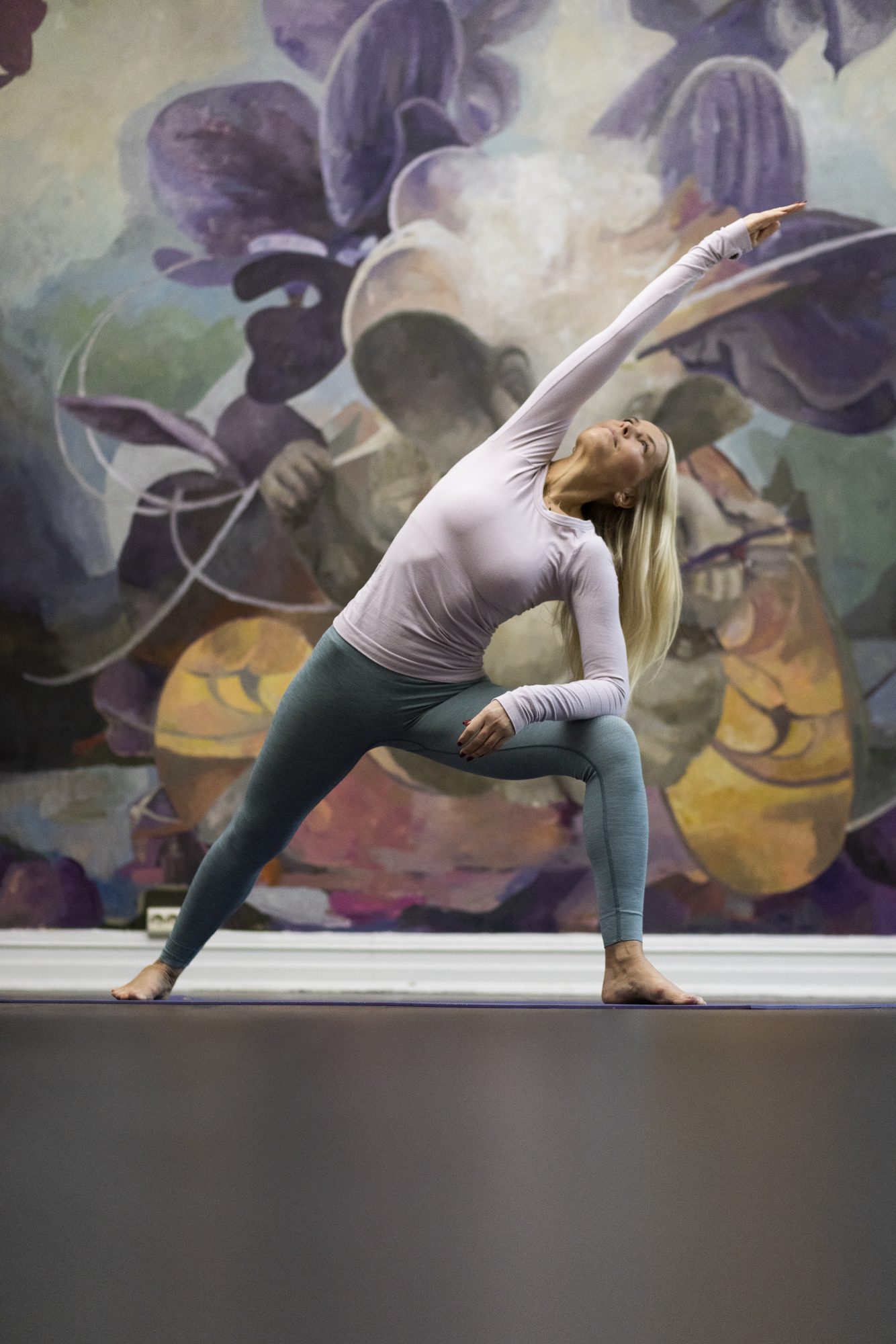 Vibeke Klemetsen foran fargerik vegg med dempede farger i sitt yogastudio