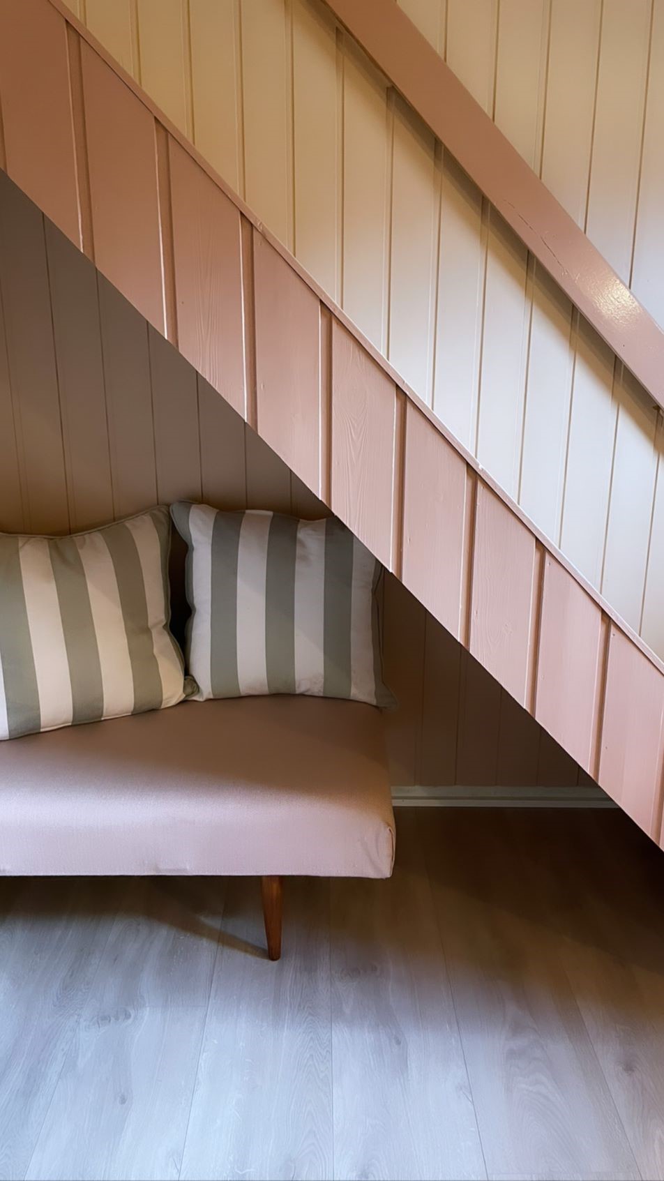 Trapp ned til kjeller med sofa under trapp. Foto.