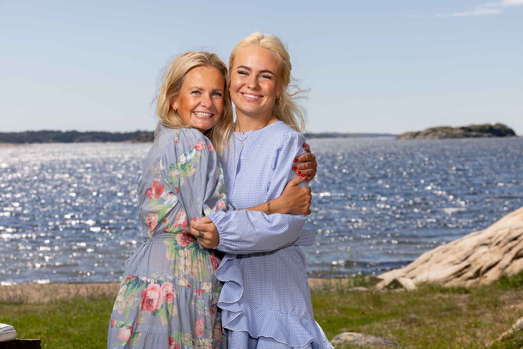 Mor og datter poserer foran havet.