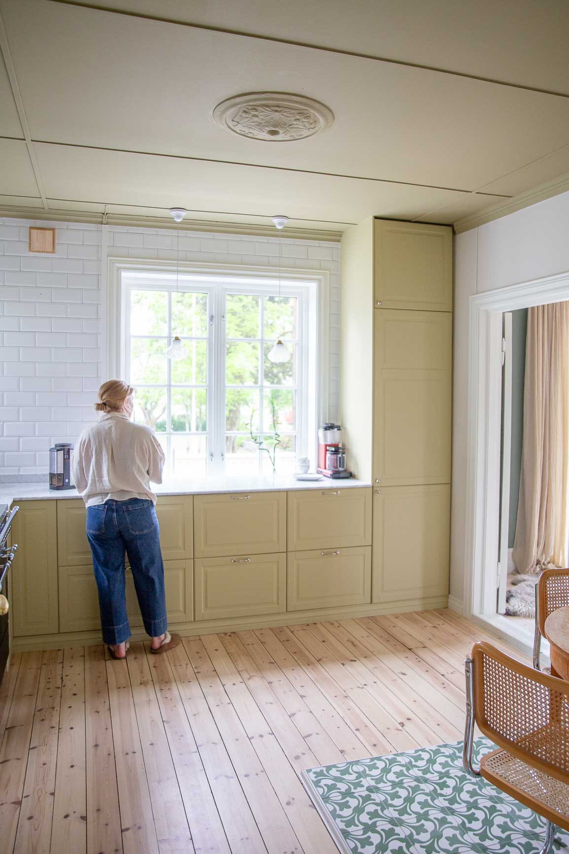Kvinne ved kjøkkenvindu i gult kjøkken, 8583 Earthy Yellow, 8625 Khaki Yellow i tak.
